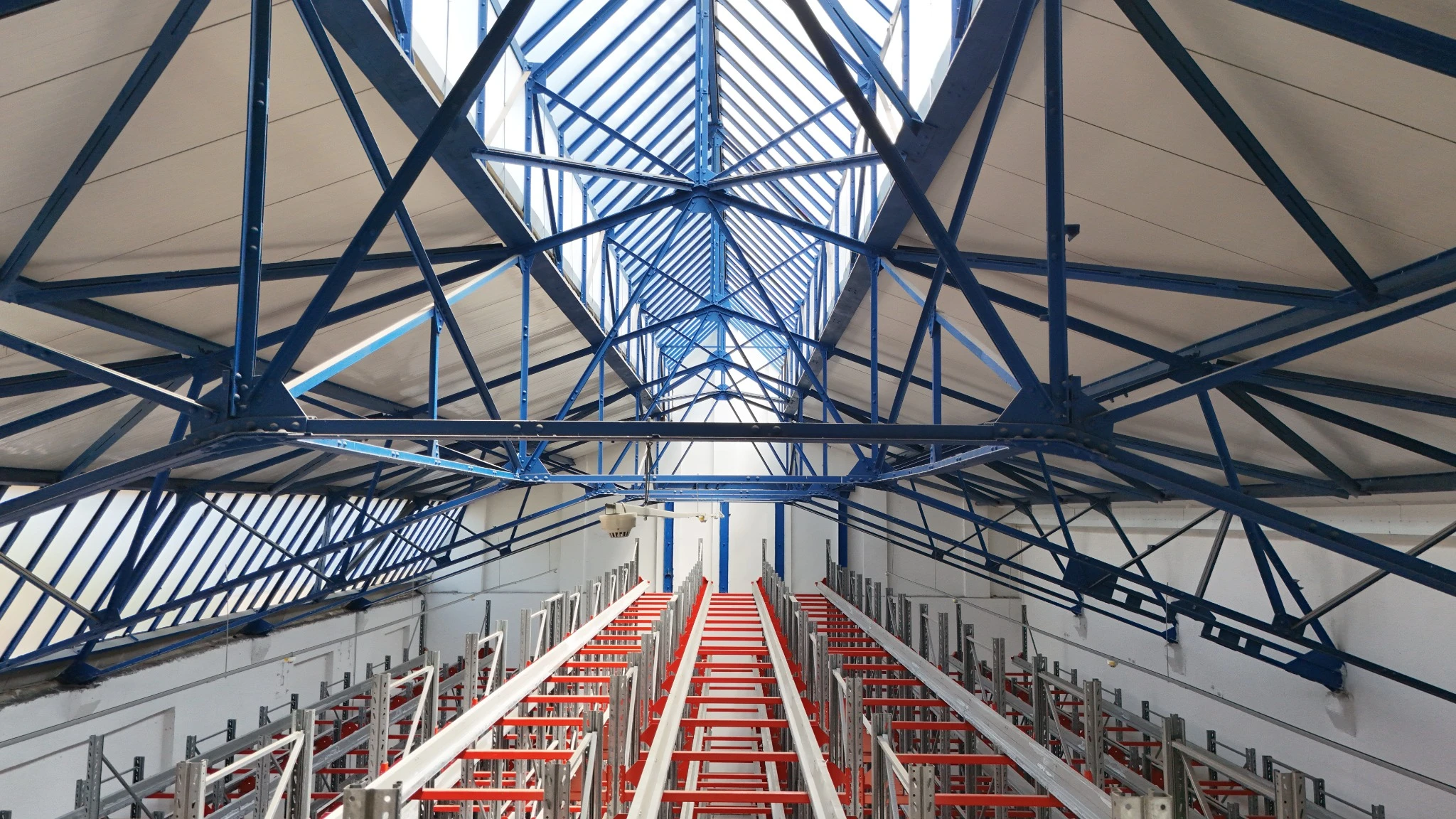 Warehouse interior with blue steel roof structure and pallet racking